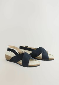 Sandales compensées en suède bleu marine avec un design à croisillons et une sangle arrière ajustable ; semelle intérieure texturée et semelle en caoutchouc pour une meilleure adhérence.