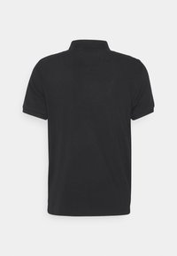 Camisa de polo negra con mangas cortas y dobladillo recto, que presenta un cuello clásico y una textura de algodón suave. Sin patrones ni acentos visibles.