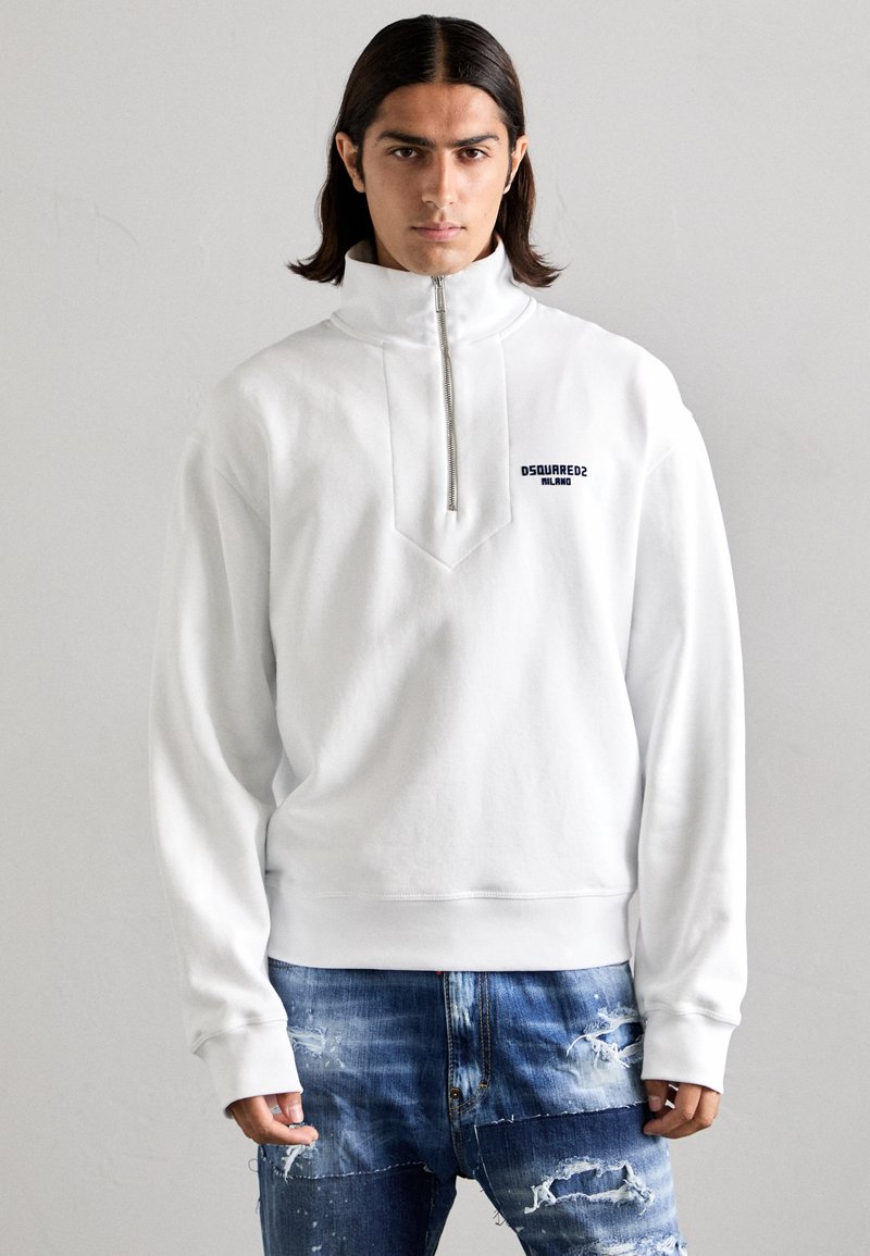 Witte pullover trui met hoge kraag, ritssluiting en een diamantvormig ontwerp op de borst. Kenmerkt een logo in marineblauw.