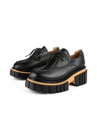 Zwarte leren schoenen met een zware zwarte plateauzool en houten accent. Voorzien van traditionele veters en een afgeronde neuzen ontwerp.