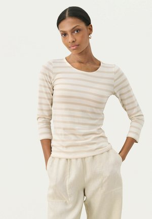 Beige und creme gestreifter Langarmtop mit rundem Ausschnitt und taillierter Passform. Kombiniert mit hellen, locker sitzenden Hosen.