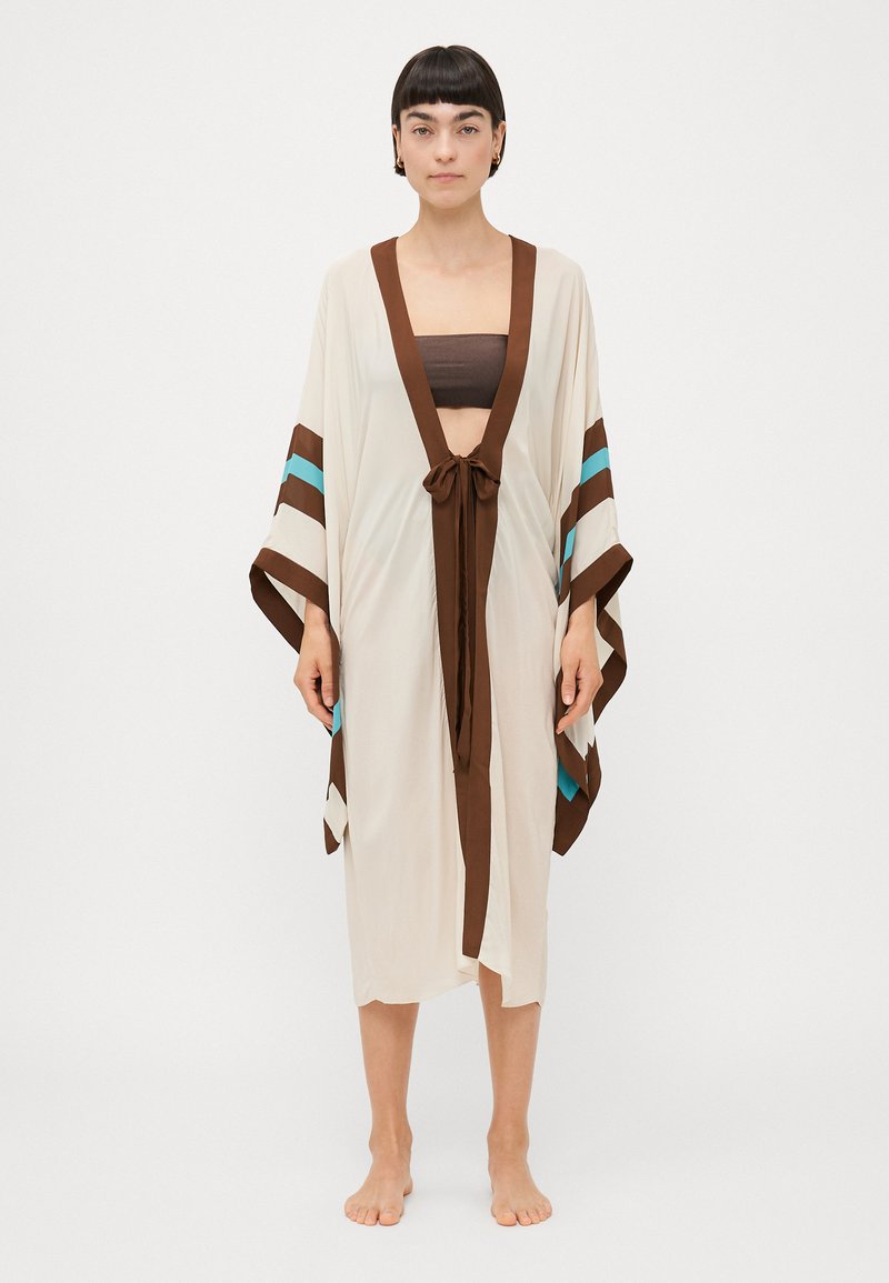 Kimono crème avec des bordures brunes, présentant des rayures teal et brunes sur les manches. Lié à la taille, design fluide, tissu léger.