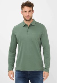 Langärmliges Poloshirt aus muted green Stoff, mit umgeschlagenem Kragen, einer Drei-Knopf-Leiste und einer Brusttasche mit genähten Details.