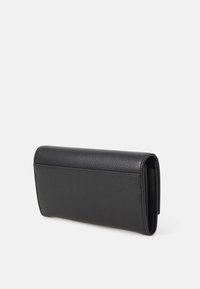 Portefeuille en cuir noir avec une texture lisse, de forme rectangulaire et au design minimaliste. Il possède une fermeture rabat et des détails de couture.
