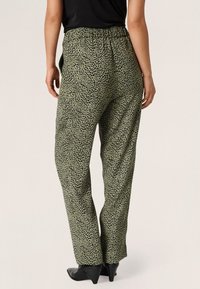 Groene broek met een relaxed fit, voorzien van een zwart dierenprintontwerp, elastische tailleband en een subtiele glanzende textuur.