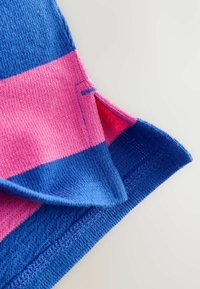 Flerfärgad stickad tyg med kraftiga rosa och blå ränder; innehåller en texturerad yta och ett accentmönster vid kanterna.