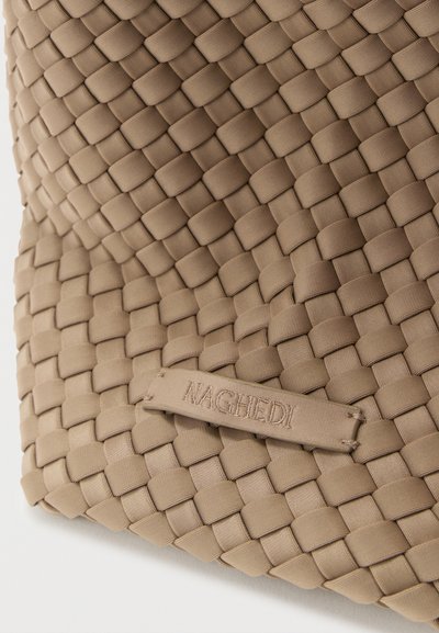 Μπεζ υφαντό υφασμάτινο τσάντα με υφή στην επιφάνεια, με ορθογώνιο σχήμα και εγχάρακτη ετικέτα της μάρκας, προσθέτοντας μια διακριτική σχεδιαστική λεπτομέρεια.