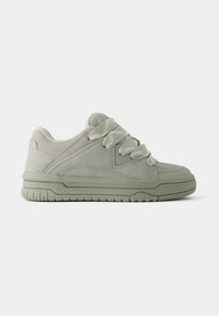 Hellgraue Sneakers mit einem Obermaterial aus Wildleder und Textil, ausgestattet mit strukturierten Gummisohlen, dicken Schnürsenkeln und Polsterung um den Knöchel.