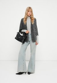 Kimono s leopardím potiskem, šedý rolák, světle modré zvonové džíny a černá texturovaná kabelka s zkrouceným uchem.