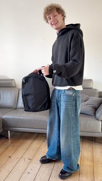 Črn nahrbtnik z gladkim, mat zaključkom. Pravokotne oblike, z zadrgo zaprtimi predeli in oblazinjenim ročajem. Nosen priložnostno.