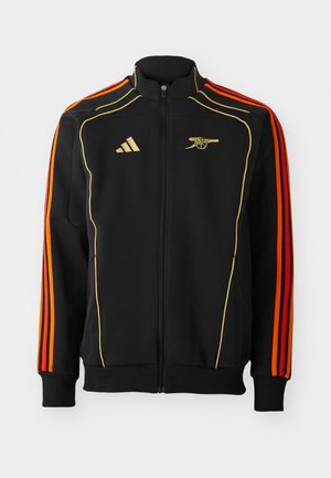 Black zip-up jacket with gold and orange accents. Features three orange stripes on sleeves and a logo on the chest. Made from soft fabric.