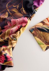 Stoff mit Blumenmuster in lebendigen Pink-, Lila- und Grüntönen. Das Material ist weich und leicht glänzend und zeigt ein gerafftes Design.