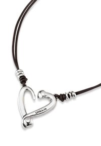 Colgante en forma de corazón plateado con acabado pulido sobre un cordón de cuero oscuro, con acentos metálicos decorativos a lo largo de la cadena.