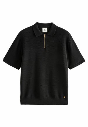 Polo noir à manches courtes avec devant texturé, fermeture éclair dorée au col, manches unies, et petit logo doré près de l'ourlet.