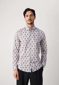 Πουκαμίσα σε λευκό βαμβάκι με λουλουδάτο σχέδιο σε μπλε, ροζ και καφέ. Διαθέτει μακριά μανίκια και κανονικό γιακά.