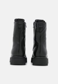Czarne skórzane botki za kostkę o eleganckim designie, z bocznym zamkiem błyskawicznym, uchwytem na pięcie oraz masywną czarną gumową podeszwą. Gładka faktura.