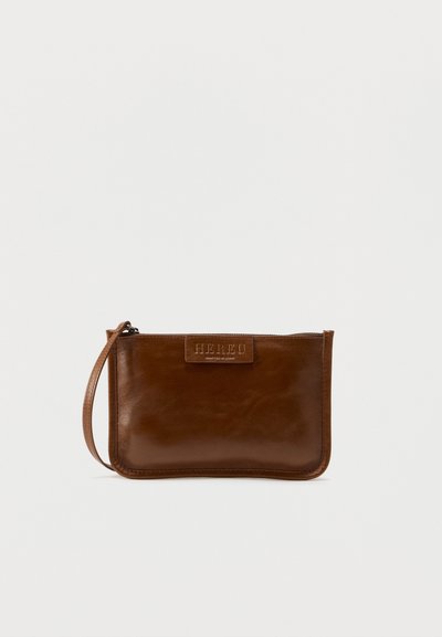 Καφέ δερμάτινο τσαντάκι χειρός με λείο υφή, κλείσιμο με φερμουάρ και λουράκι για τον καρπό. Διαθέτει ανάγλυφο λογότυπο στο μπροστινό μέρος. Συμπαγής και ορθογώνιο σχήμα.