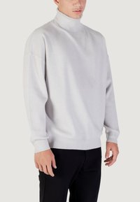 Lichtgrijze turtleneck trui met een ontspannen pasvorm, geribde manchetten en zoom. Gemaakt van zachte breimateriaal, heeft het verlaagde schouders voor extra comfort.