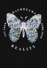 Tela negra con un gran diseño de mariposa detallado en un patrón de camuflaje azul y verde, con acentos plateados, rodeado de texto blanco.