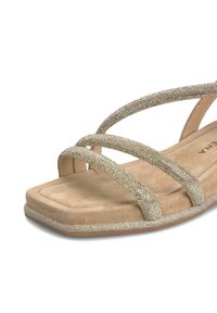 Sandales dorées avec des orteils carrés plats et des straps entrecroisés ornés de strass, présentant une semelle intérieure texturée ressemblant à du daim.