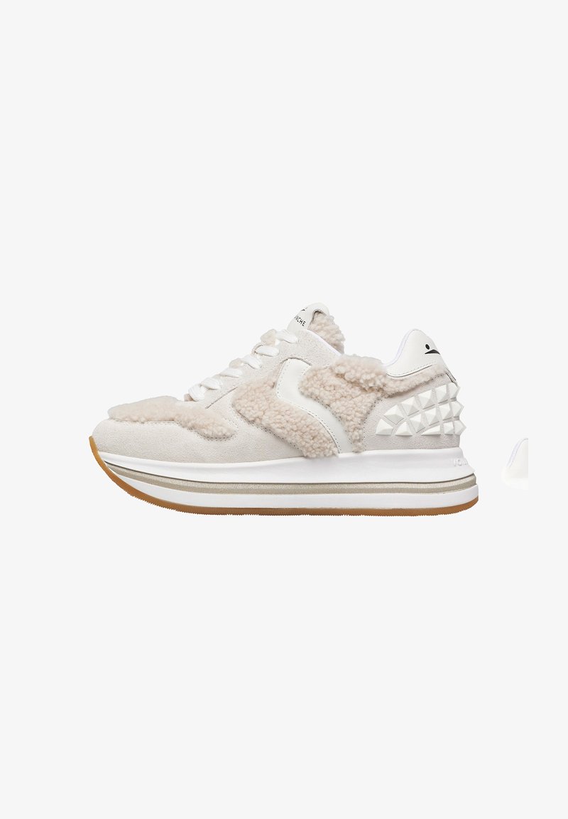 Sneakers beige in suede con texture pelosa, dettagli bianchi e borchie a forma di piramide. Presentano una spessa suola bianca con una base in gomma.