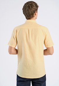 Korte mouwen gele shirt van een gestructureerde stof, met een button-down kraag en een gebogen zoom, voorzien van een plooitje aan de achterzijde.