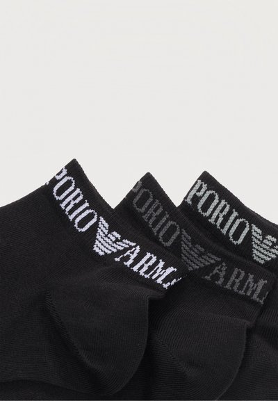 Τρία ζευγάρια μαύρες κάλτσες αστραγάλου τοποθετημένες επικαλυπτόμενες, το καθένα με την επιγραφή "Emporio Armani" και το λογότυπο αετού της μάρκας κεντημένα σε λευκό στο μανίκι.