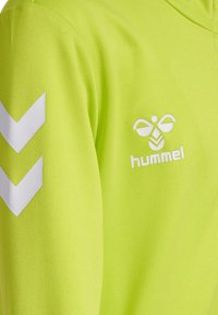 Jaskrawozielona bluza z kapturem z białymi wzorami w kształcie chevron na ramionach oraz logo na piersi. Wykonana z teksturowanego, oddychającego materiału.