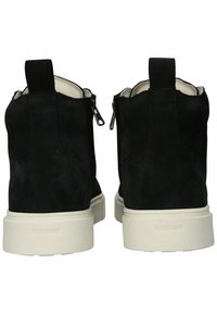 Botas de tobillo de ante negro con una superficie texturizada, con cremalleras laterales y suelas de goma blanca. Logotipo de la marca grabado en el tacón.