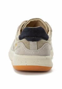Sportlicher Schuh mit einem beige-farbenen Stoffoberteil, grauem Wildleder-Fersenteil und orangefarbener Gummisohle. Verfügt über gestickte Akzente und einen gepolsterten Kragen.