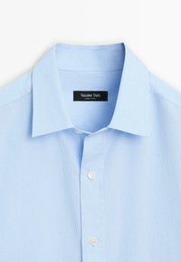 Jasnoniebieska koszula w paski z klasycznym kołnierzykiem, białymi guzikami i czarną metką z napisem "Massimo Dutti". Wykonana z gładkiego materiału.