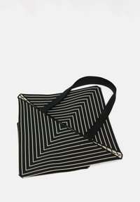 Borsa a spalla a righe bianche e nere con un design geometrico, in tessuto, con manici lunghi neri e forma pieghevole.