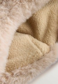 Interno foderato in pelliccia sintetica con un morbido tessuto tinta sabbia; presenta un bordo esterno beige chiaro con un'aspetto soffice.