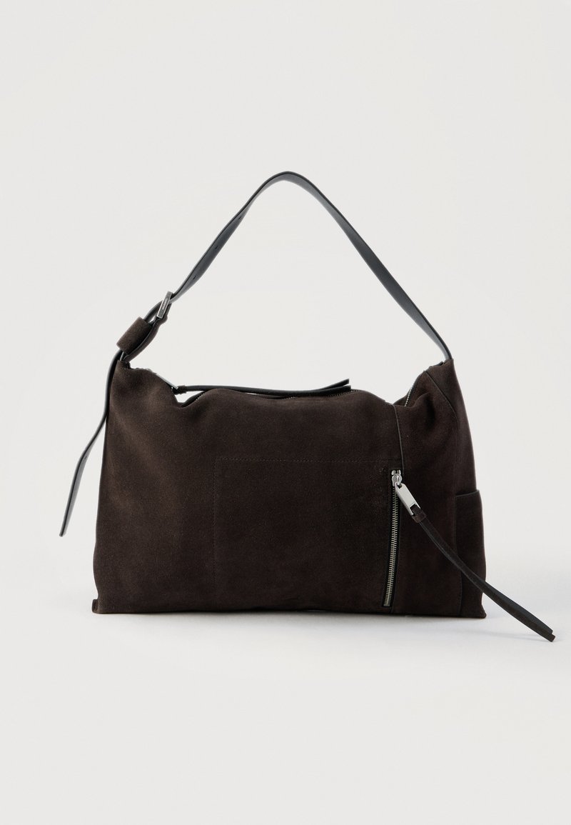 Σκούρα καφέ σουέτ τσάντα ώμου με φαρδιά τιράντα, εμπρόσθια τσέπη με φερμουάρ και μακριά δερμάτινη ταινία, και μαλακό, χαλαρό σχήμα.