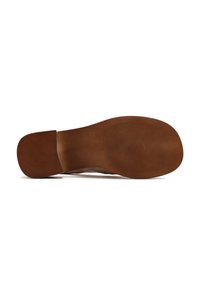 Suola di gomma marrone di una scarpa con scanalature testurizzate e una sezione del tallone piatta. Il design è minimalista con una finitura liscia.