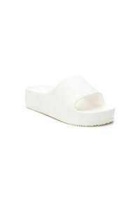 Sandalia de plataforma blanca, tipo slide, con punta abierta, fabricada en material sintético suave. Presenta una correa ancha y suela texturizada para mayor agarre.