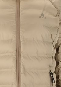 Beige dunjakke med lodret lynlåslukning, quiltet tekstur og et lille gråt logo på venstre side. Indeholder sidelomme med lynlås.