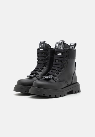Bottines en cuir noir avec une épaisse semelle en caoutchouc, œillets en métal et marquage contrastant sur les languettes et les lacets.