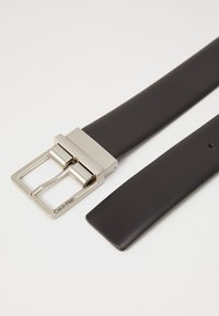 Black leather belt with a silver metal buckle. The buckle features a simple rectangular design with a tang and prong closure.