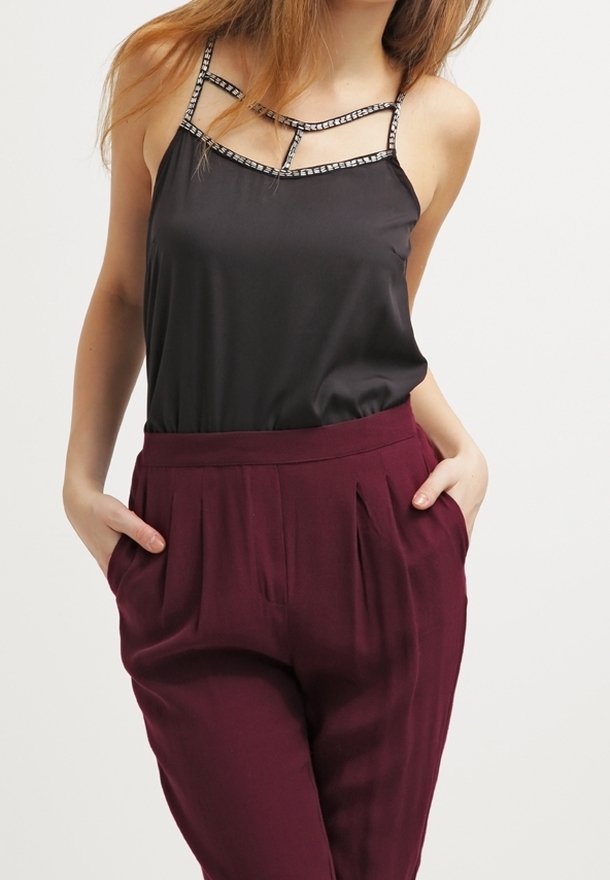 Débardeur en satin noir avec bretelles décoratives, associé à un pantalon plissé bordeaux avec poches latérales. Texture lisse et coupe décontractée.