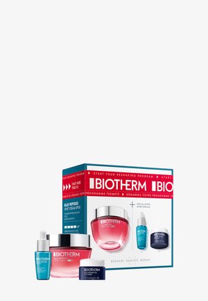 Coffret de soins Biotherm dans une boîte bleue et rouge avec un pot rose, un sérum bleu et une crème pour les yeux. Contient les noms des produits et les détails sur le SPF.