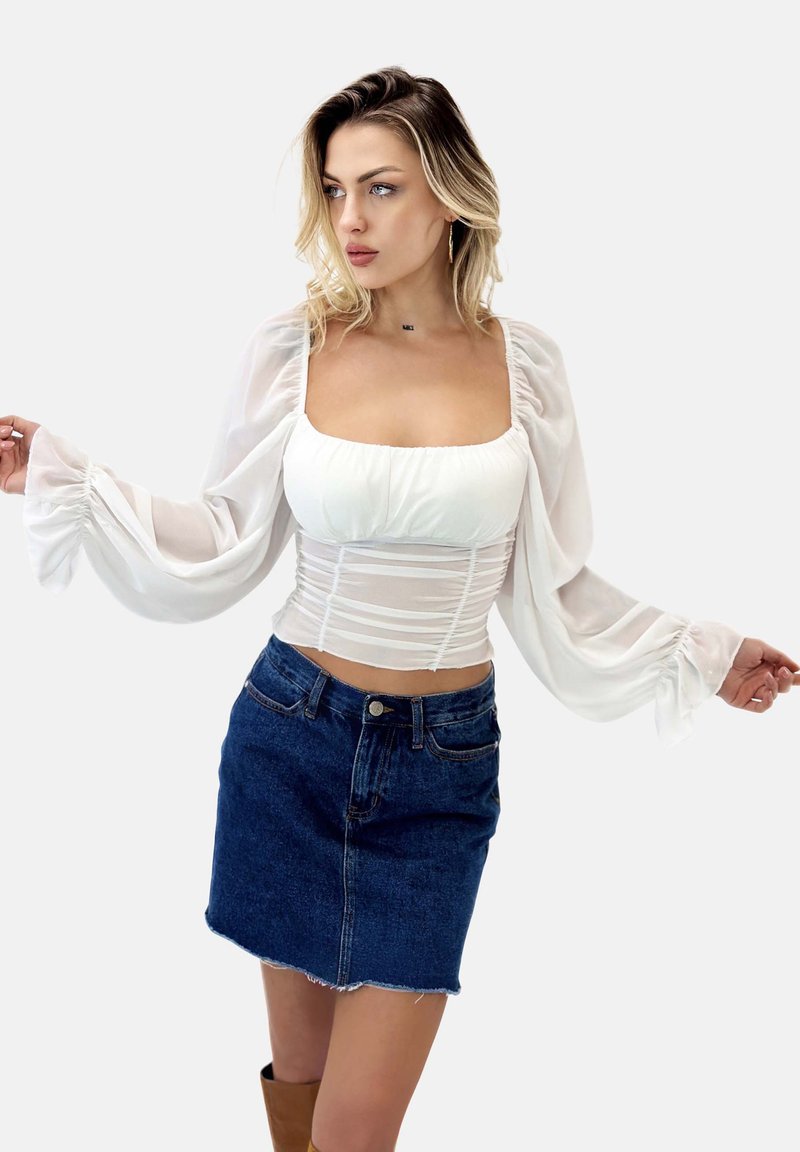 Weiße, transparente Bluse mit puffierten Ärmeln, tailliertem Oberteil und einem runden Ausschnitt, kombiniert mit einem dunklen Denim-Minirock mit fransigem Saum.