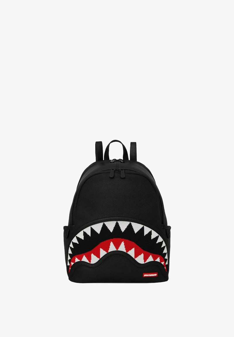 Zaino nero con design a bocca di squalo, caratterizzato da denti bianchi e dettagli rossi. Realizzato in tessuto, con due spallacci regolabili e chiusura con zip.