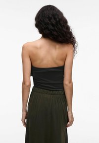 Czarny, prążkowany top bez ramiączek w połączeniu z długą oliwkową spódnicą, charakteryzującą się miękką fakturą i elastycznym pasem, widok z tyłu.