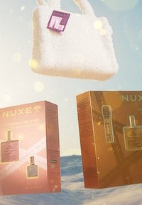 Bolso de mano blanco y esponjoso con asas, que presenta una etiqueta morada. Dos cajas de productos NUXE, una rosa y otra dorada, con detalles visibles del producto.
