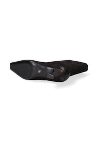 Chaussure en daim noir à semelle plate, à bout rond et au design minimaliste. Elle se distingue par une semelle extérieure noire lisse et un détail discret du logo de la marque.