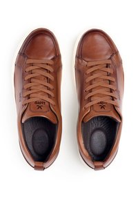 Brązowe skórzane sneakersy z zaokrąglonym noskiem, tonowymi sznurówkami, minimalistycznym designem oraz kontrastującą kremową gumową podeszwą. Posiadają logo na języku.