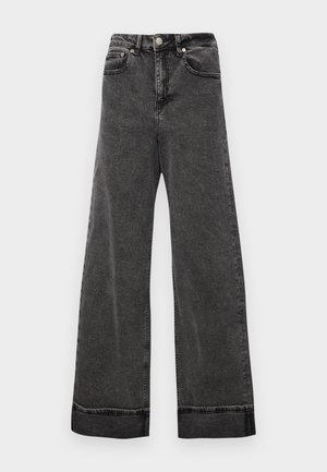 Platas kāju augstās melnas džinsus, kas izgatavoti no denima, ar pogu aizdari, piecām kabatām un neapstrādātiem apakšmalēm pie potītēm.