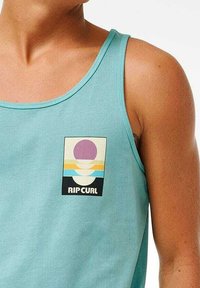 Un débardeur bleu clair avec un logo avant comportant des graphiques circulaires et des ondes en violet, jaune et blanc. Fabriqué en tissu en coton doux.