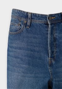 Vaqueros de mezclilla de color azul oscuro con cintura alta, cinco bolsillos, costuras en contraste y cierre de botón metálico. Textura suave con un ligero desgastado.
